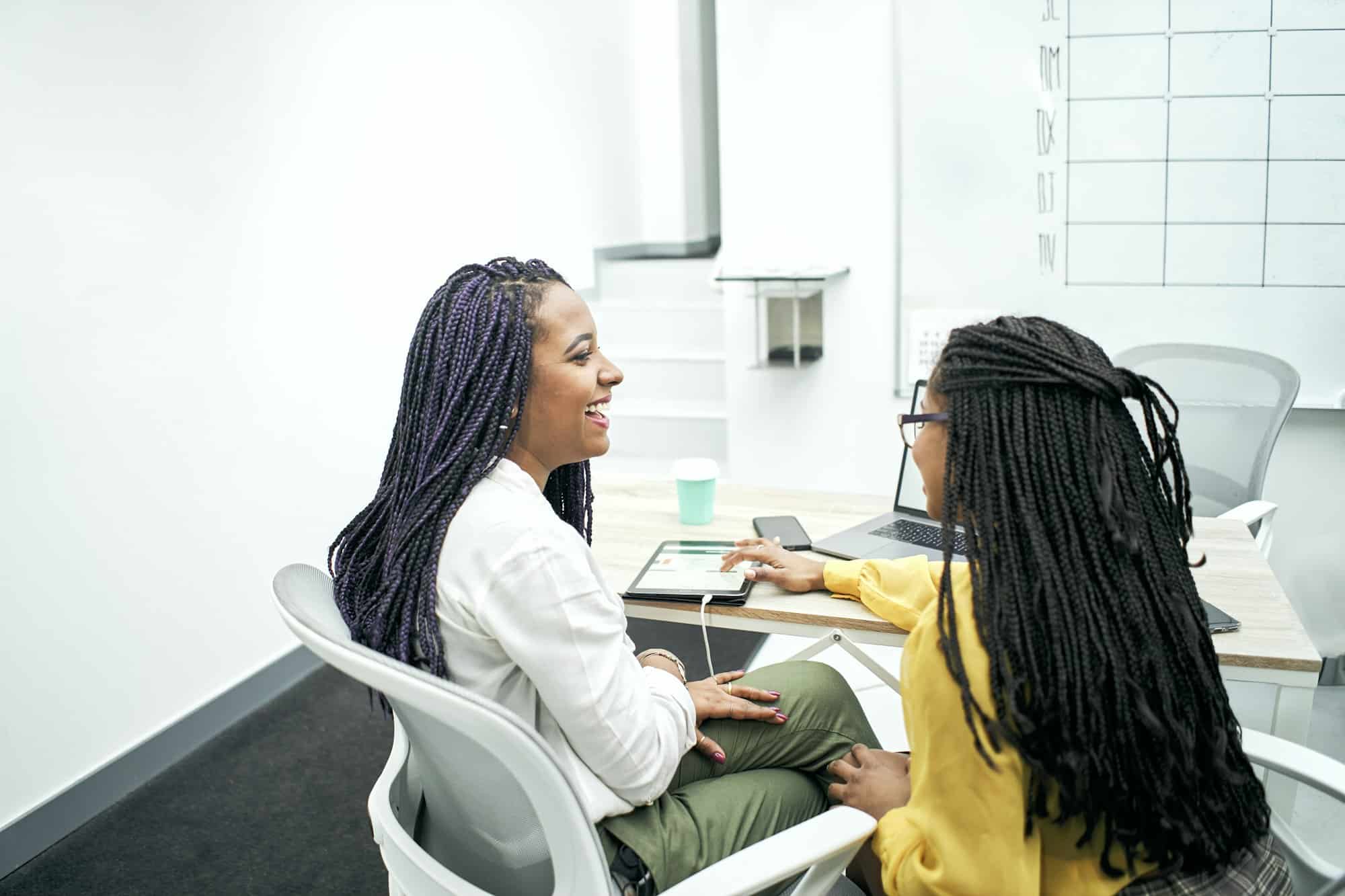 Two young black women working in the office. Reviewing analytical